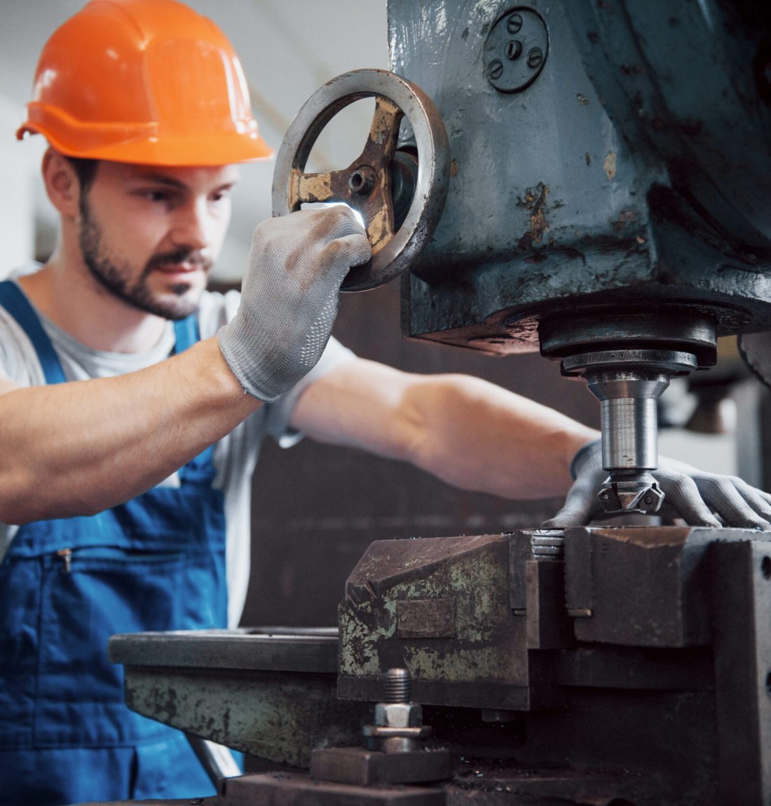 Portrait of a young worker in a hard hat at a large metalworking plant. The engineer serves the machines and manufactures parts for gas equipment.